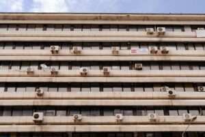 Multi-story building facade featuring air conditioning units and windows.
