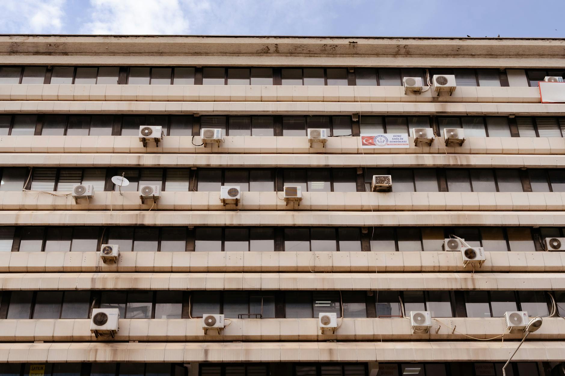 Multi-story building facade featuring air conditioning units and windows.