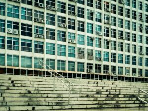 Facade of a building with multiple air conditioning units and stairs leading up.