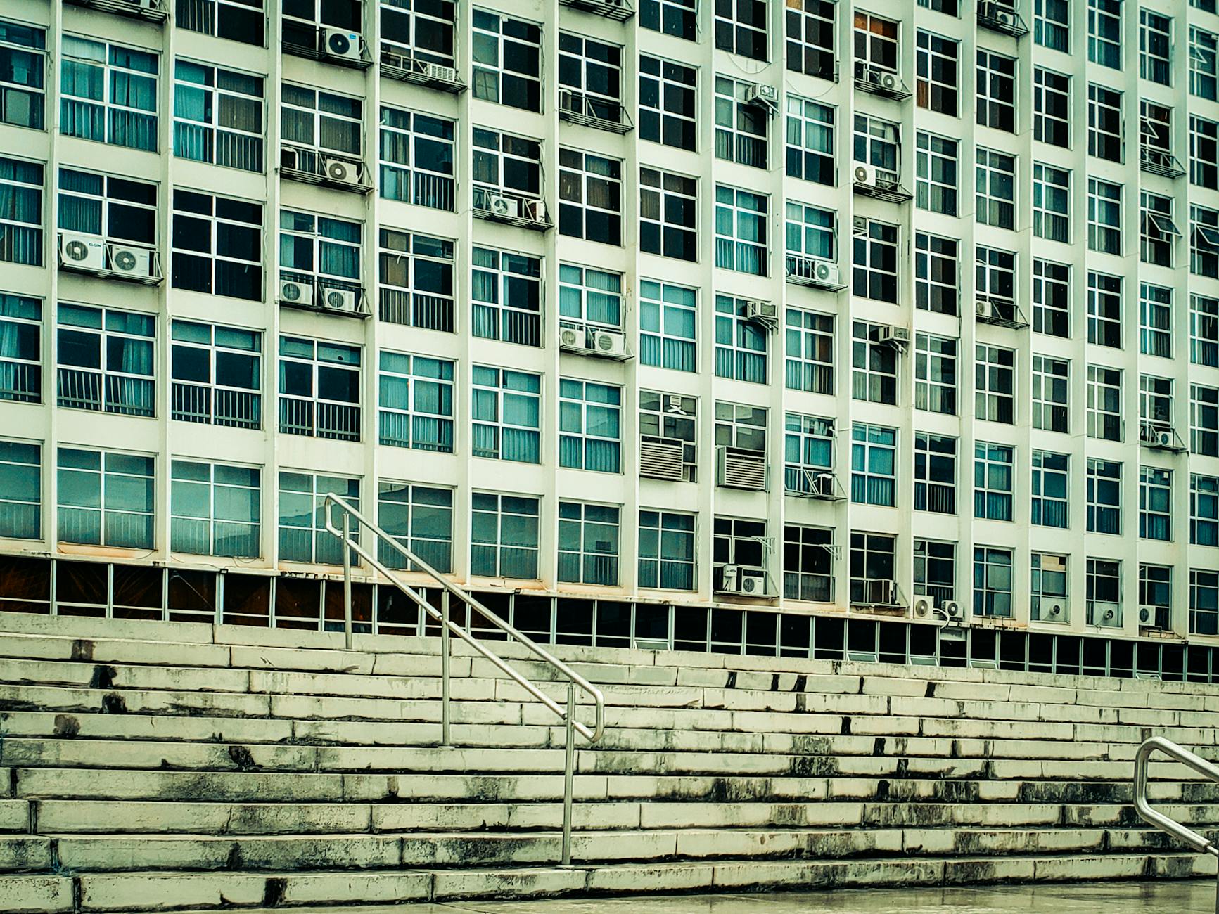 Facade of a building with multiple air conditioning units and stairs leading up.