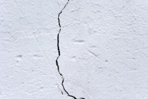 Backdrop of textured rough plaster wall with uneven surface and large crack in center