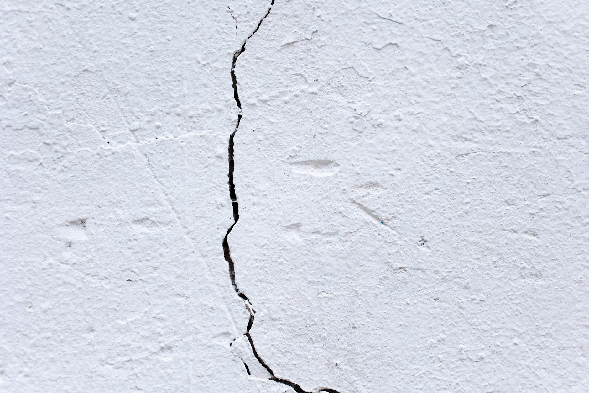 Backdrop of textured rough plaster wall with uneven surface and large crack in center