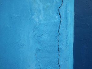 Detailed close-up of a cracked blue wall texture, revealing surface imperfections.