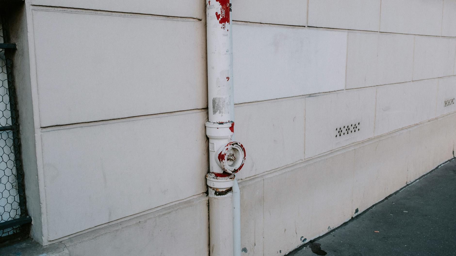 Close-up of a weathered drainpipe on an urban wall, showing signs of wear.