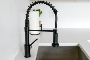 Sleek black faucet on white countertop in modern kitchen. Ideal for minimalist and contemporary designs.