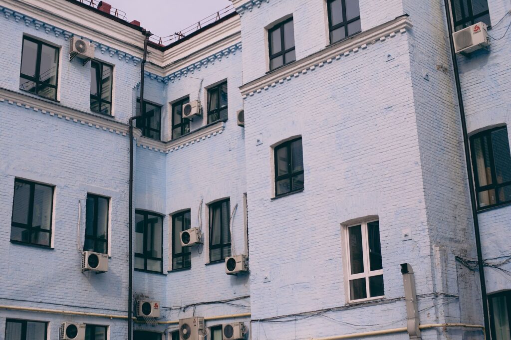 Aged building facade with windows and air conditioning split system on front wall in town