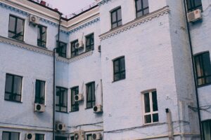 Aged building facade with windows and air conditioning split system on front wall in town