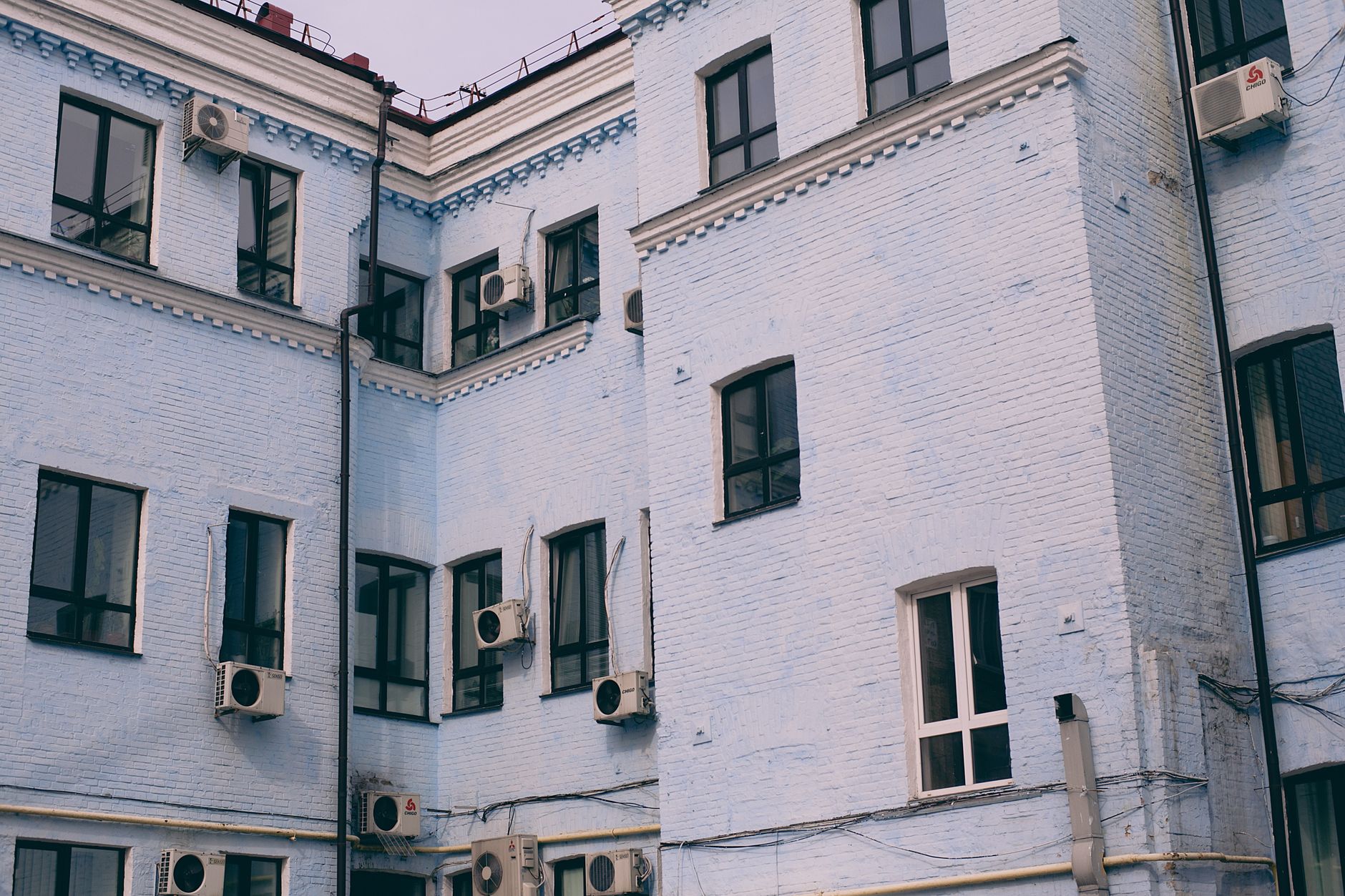 Aged building facade with windows and air conditioning split system on front wall in town