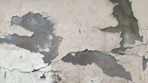 Detailed close-up of a worn-out wall with peeling plaster and visible cracks.