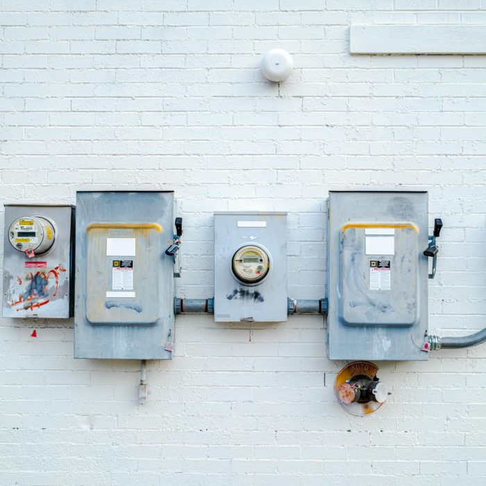 Electrical boxes and power meters mounted on a white brick wall.