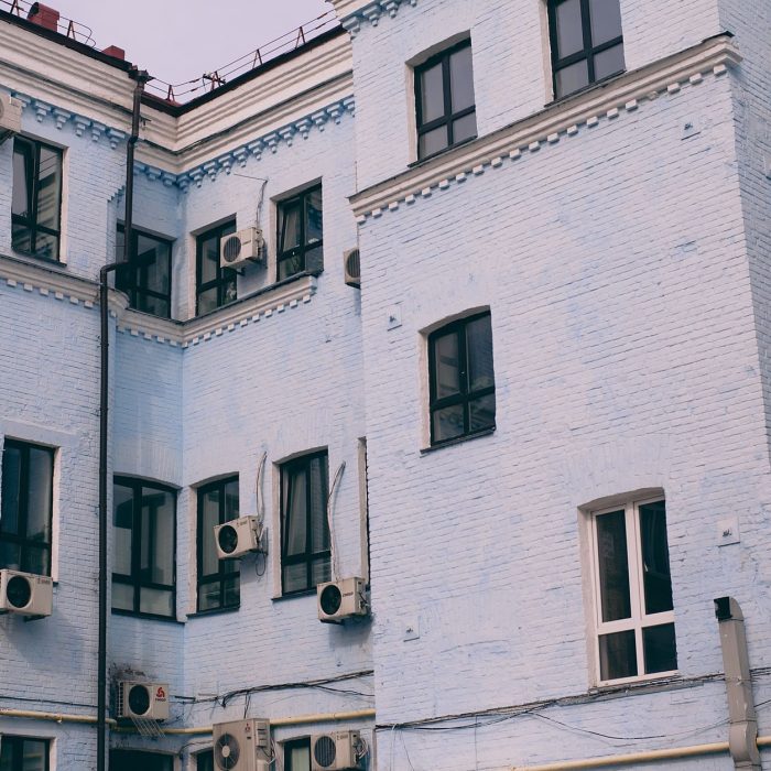 Aged building facade with windows and air conditioning split system on front wall in town