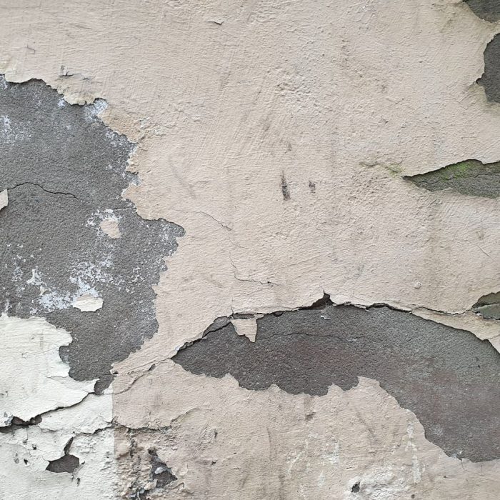 Detailed close-up of a worn-out wall with peeling plaster and visible cracks.