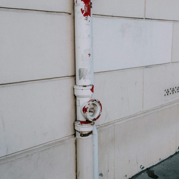 Close-up of a weathered drainpipe on an urban wall, showing signs of wear.